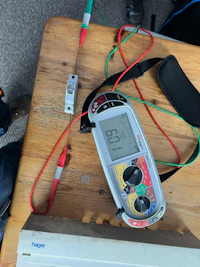 a digital multimeter on a table next to a laptop