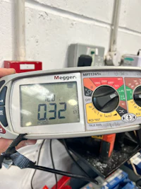 a person holding a digital multimeter in a workshop
